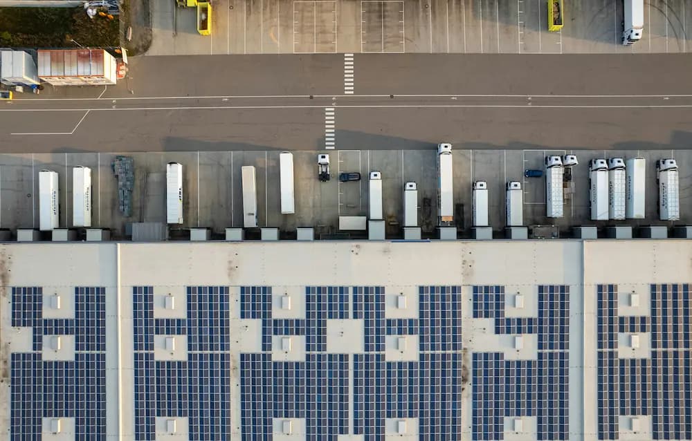 Vue aérienne d'un centre logistique avec camions aux quais de chargement et panneaux solaires
